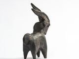 statue of a goat with horns on its back on a white surface