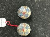 two small glass beads on a black surface with a red string