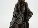 une statue représentant un homme assis sur une chaise