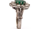 a close up of a diamond and emerald ring on a white background