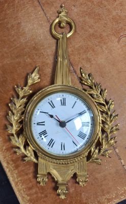 a gold clock hanging on the wall next to a brown book
