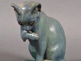une statue représentant un chat assis sur une assiette