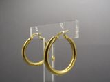 a close up of a pair of gold hoop earrings on a clear stand