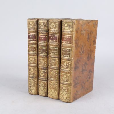 trois vieux livres posés l'un sur l'autre sur une surface blanche