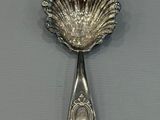 a silver spoon with a shell shaped handle on a table