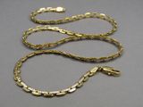 two gold chains with a snake on them on a gray surface