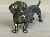 une petite statue de chien en bronze posée sur une surface blanche