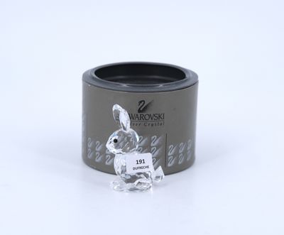 the small glass rabbit is sitting in the middle of a black container