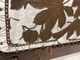 a metal plaque with leaves on it hanging on a wall