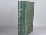 an old book with a green cover sitting on top of a table