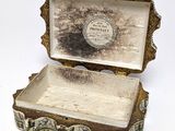 a silver box with a lid on a white surface