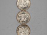 three silver coins sitting on top of each other on a table