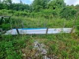 a boat that is sitting in the grass by a fence