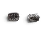 pair of black and silver cufflinks on a white surface