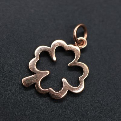 a close up of a flower pendant on a black surface
