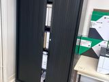a black cabinet in the corner of a room next to a desk