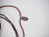 a brown beaded necklace with a silver tag on it