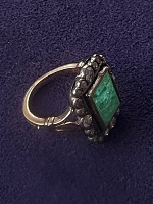 an image of a ring with a green stone surrounded by diamonds