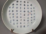 une assiette blanche avec une inscription bleue, posée sur une table