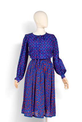 une photo d'un mannequin portant une robe bleue ornée de fleurs rouges
