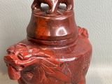 une image représentant un petit vase rouge surmonté d'un lion