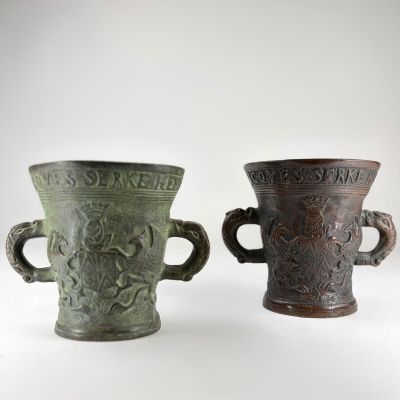 deux vases verts posés l'un à côté de l'autre sur une surface blanche
