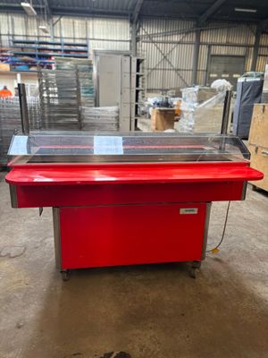 une photo d'une table rouge avec un plateau en verre dans un entrepôt