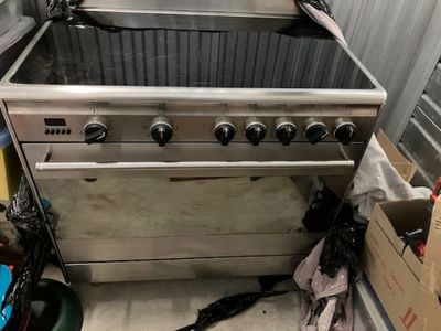 une photo d'une cuisine avec une cuisinière et quelques cartons