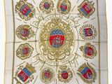 a close up of a white and gold scarf with a coat of arms on it