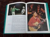 un livre ouvert sur lequel figure l'image d'un homme jouant de la guitare et d'une femme chantant
