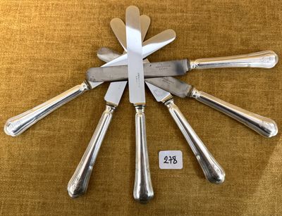 cinq couteaux et un porte-couteaux posés sur une table