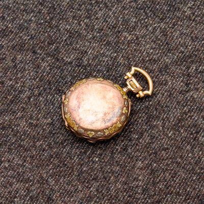 une petite montre de poche en or ornée d'une pierre rose