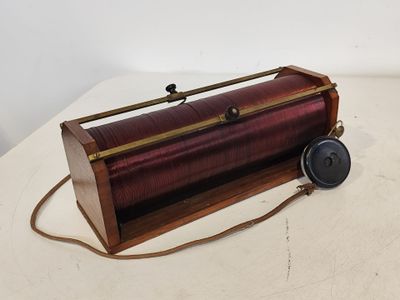 une boîte en bois à l'ancienne, munie d'une poignée en métal, posée sur une surface blanche
