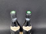 two bottles of wine sitting next to each other on a black surface