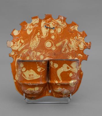 an orange and white vase sitting on top of a metal stand