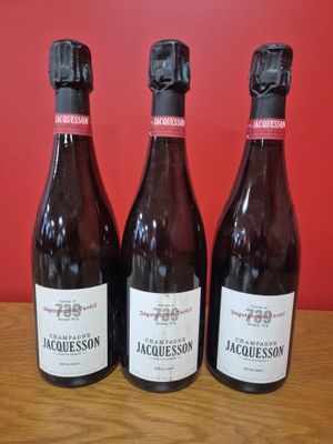 trois bouteilles de vin posées sur une table devant un mur rouge