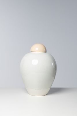 un vase blanc muni d'un couvercle en bois, posé sur une table
