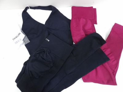 trois paires de leggings et un haut de sport posés sur une surface blanche