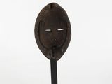a small wooden sculpture of a face on a stand