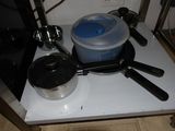 pots and pans sit on a stove top with a microwave in the background