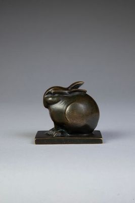 a bronze sculpture of a rabbit on a wooden base