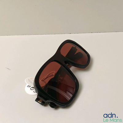 une paire de lunettes de soleil posée sur une table sur laquelle est collé un autocollant