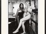 photographie en noir et blanc de deux femmes assises sur une chaise devant une bibliothèque