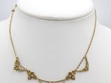 a gold necklace on a mannequin neck with a flower design