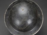 an old metal bowl sitting on top of a black table