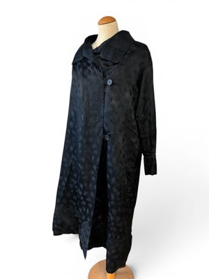 une image d'un manteau noir sur un support de mannequin