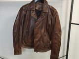 une veste en cuir marron suspendue à un portant dans une pièce