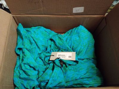 une boîte contenant une chemise bleue et sur laquelle est accrochée une étiquette