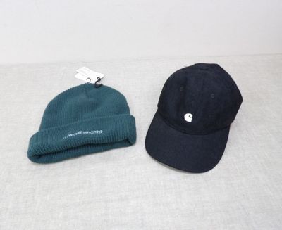 Deux chapeaux sont posés sur un lit, avec une étiquette attachée dessus.