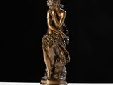 a bronze statue of a woman sitting on a rock